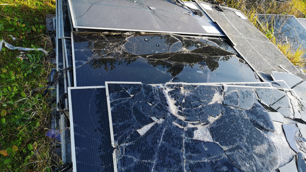 Stack of broken black solar panels laying on the grass